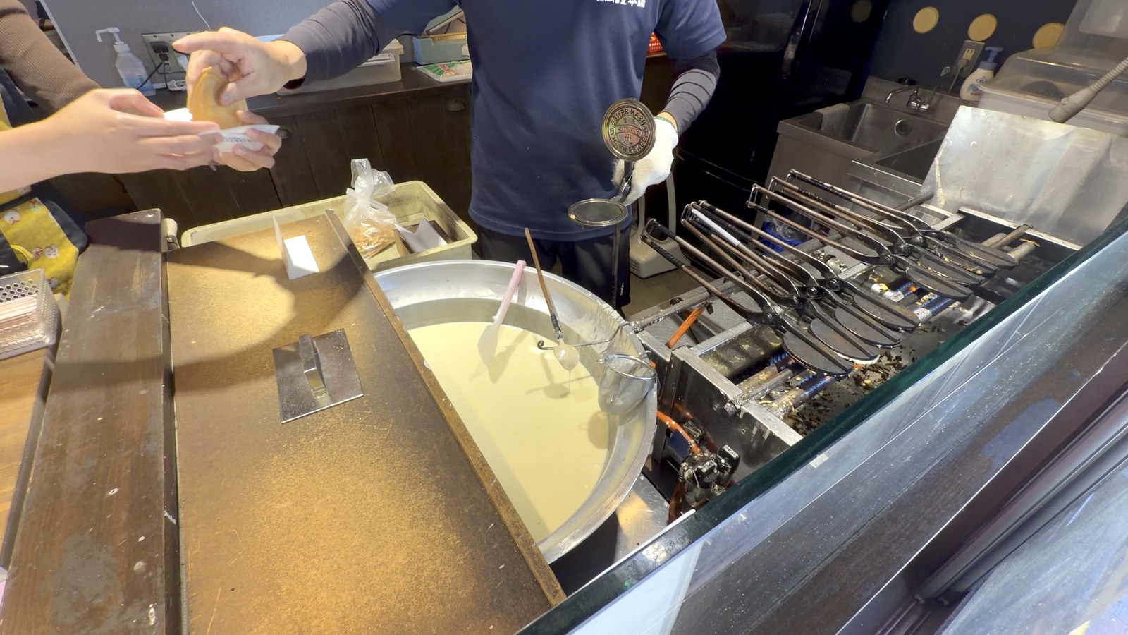 焼きたての炭酸せんべいを、隣の店員さんへ渡すところ