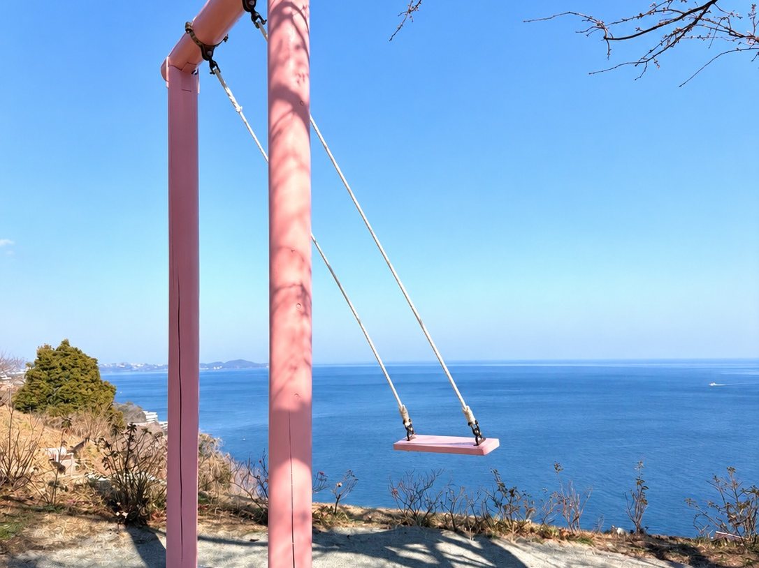 海を背にしたピンク色の空飛ぶブランコ