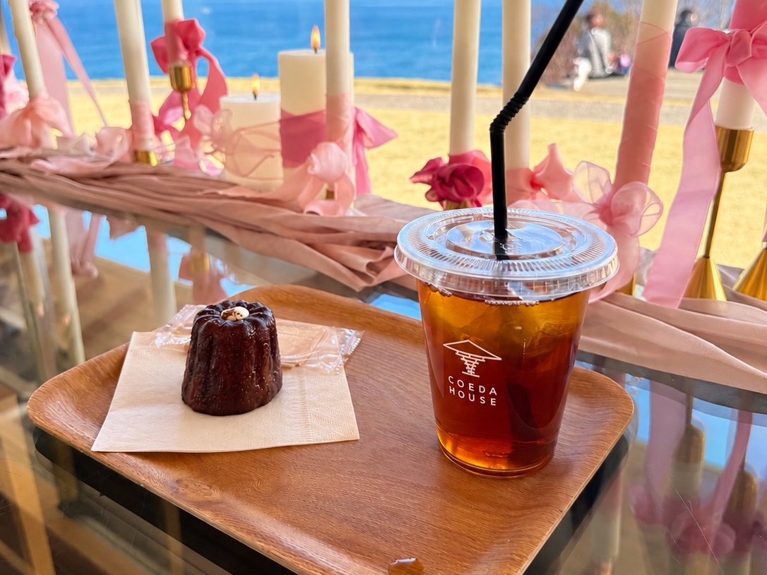 COEDA HOUSE のカヌレとアイスティー。窓辺のキャンドル装飾の向こうに海