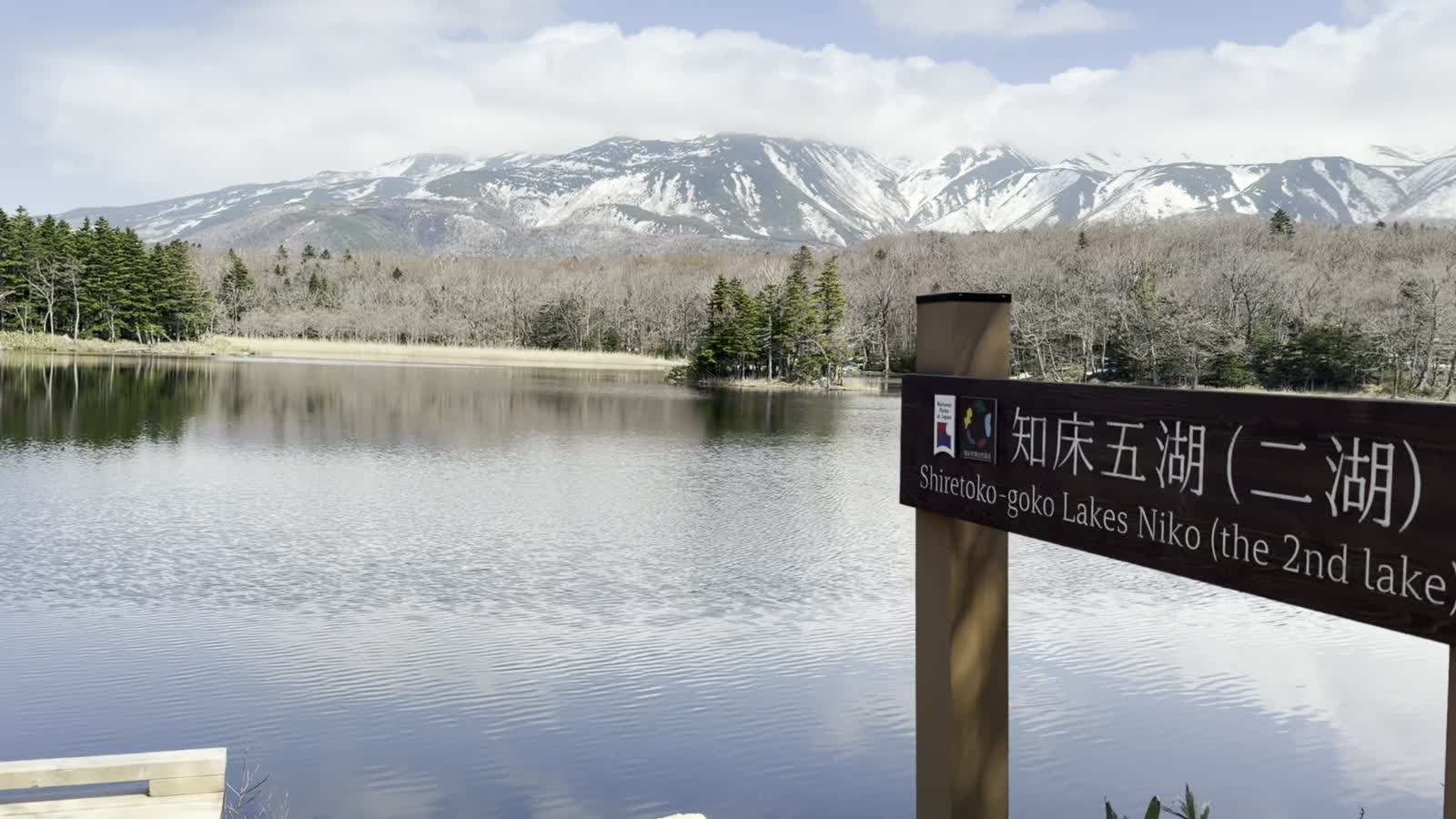 「知床五湖(二湖)」の標識と、その向こうの湖と知床連山